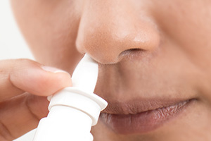 Frau verwendet Nasenspray gegen ihre Allergiesymptome