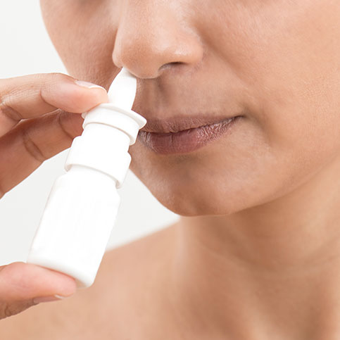 Frau verwendet Nasenspray gegen ihre Allergiesymptome